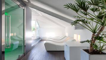 Un intérieur moderne avec un comptoir d’accueil blanc aux lignes courbes, un mur de verre et une plante en pot.