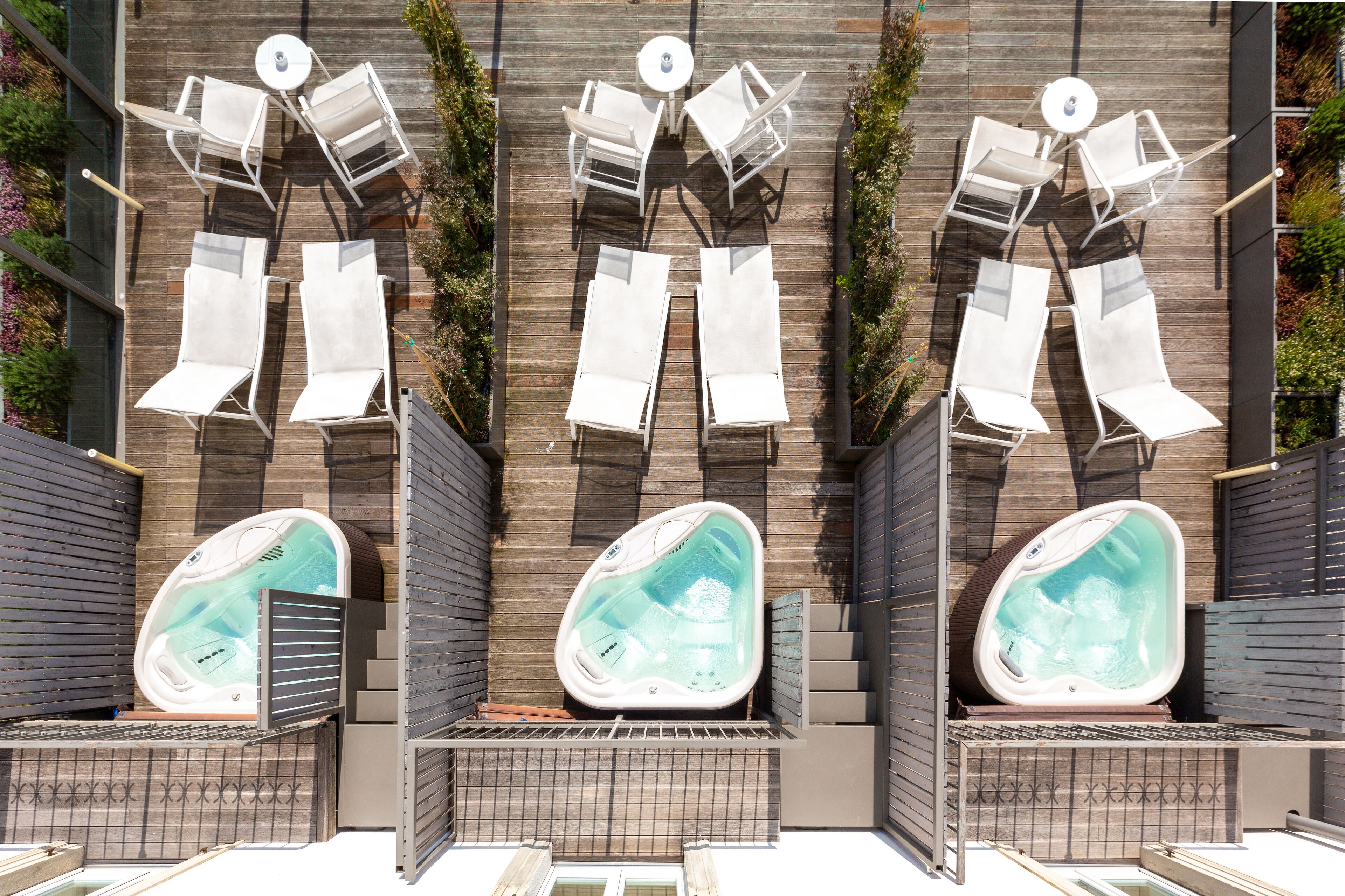 A rooftop pool area with lounge chairs and a hot tub.