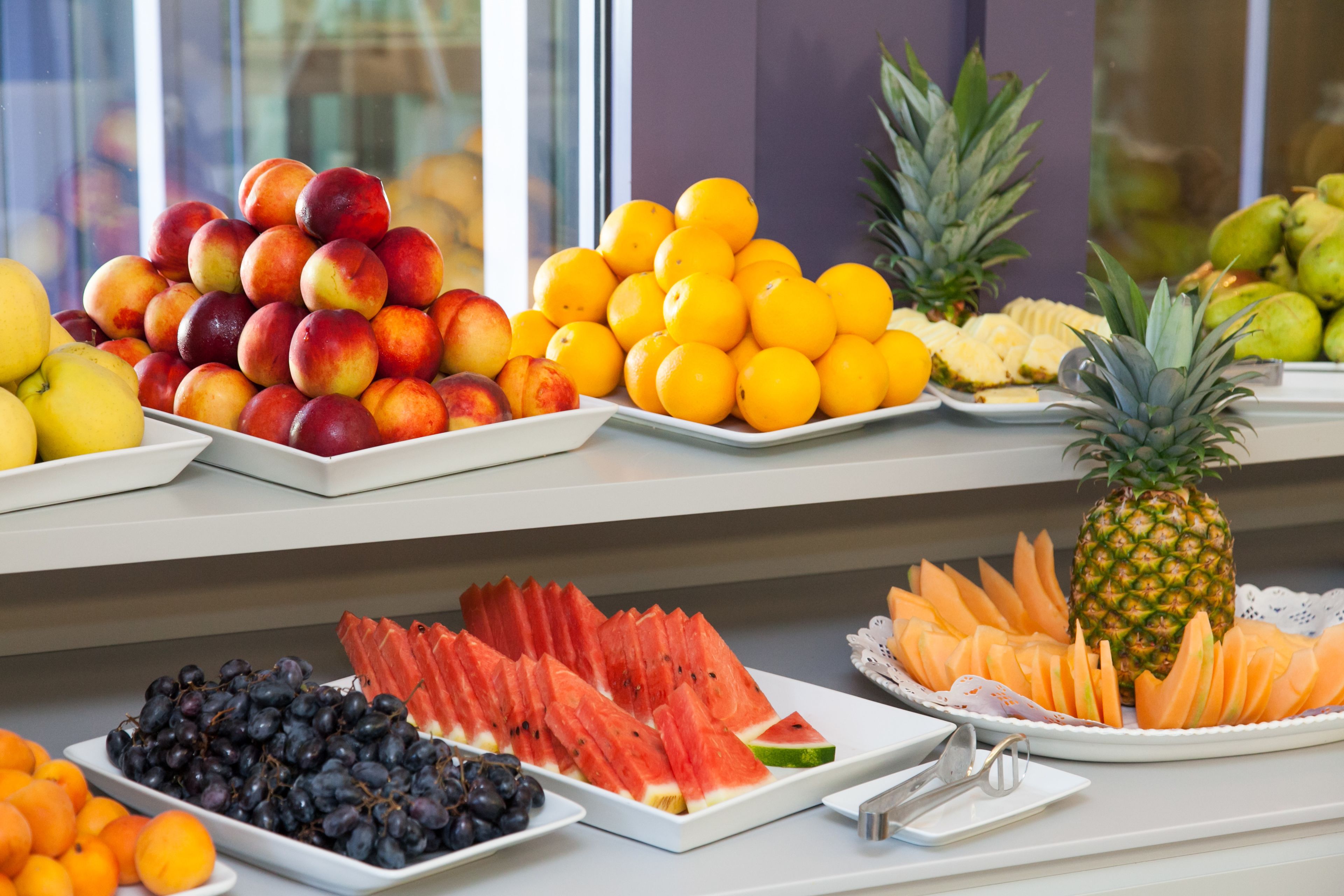 A fruit display with various types of fruits including apples, oranges, and watermelons.