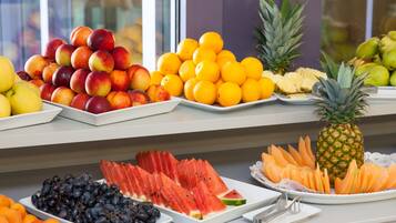 A fruit display with various types of fruits including apples, oranges, and watermelons.