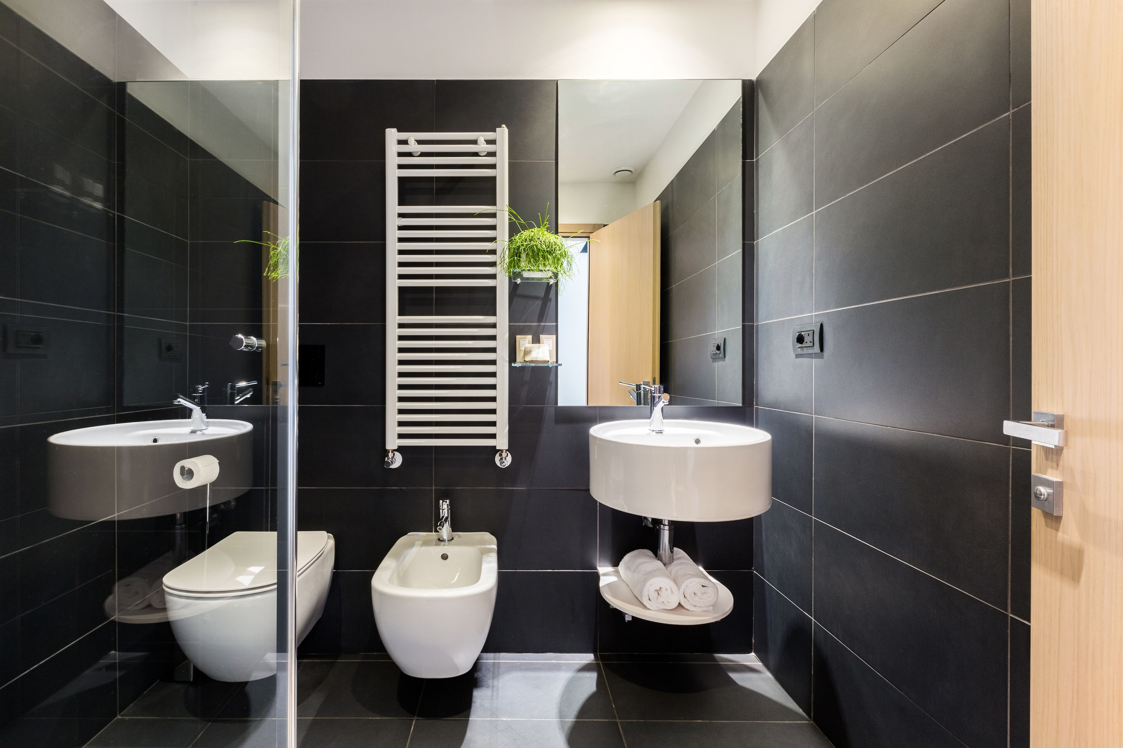 A modern bathroom with a bidet, toilet, and sink, all in white.