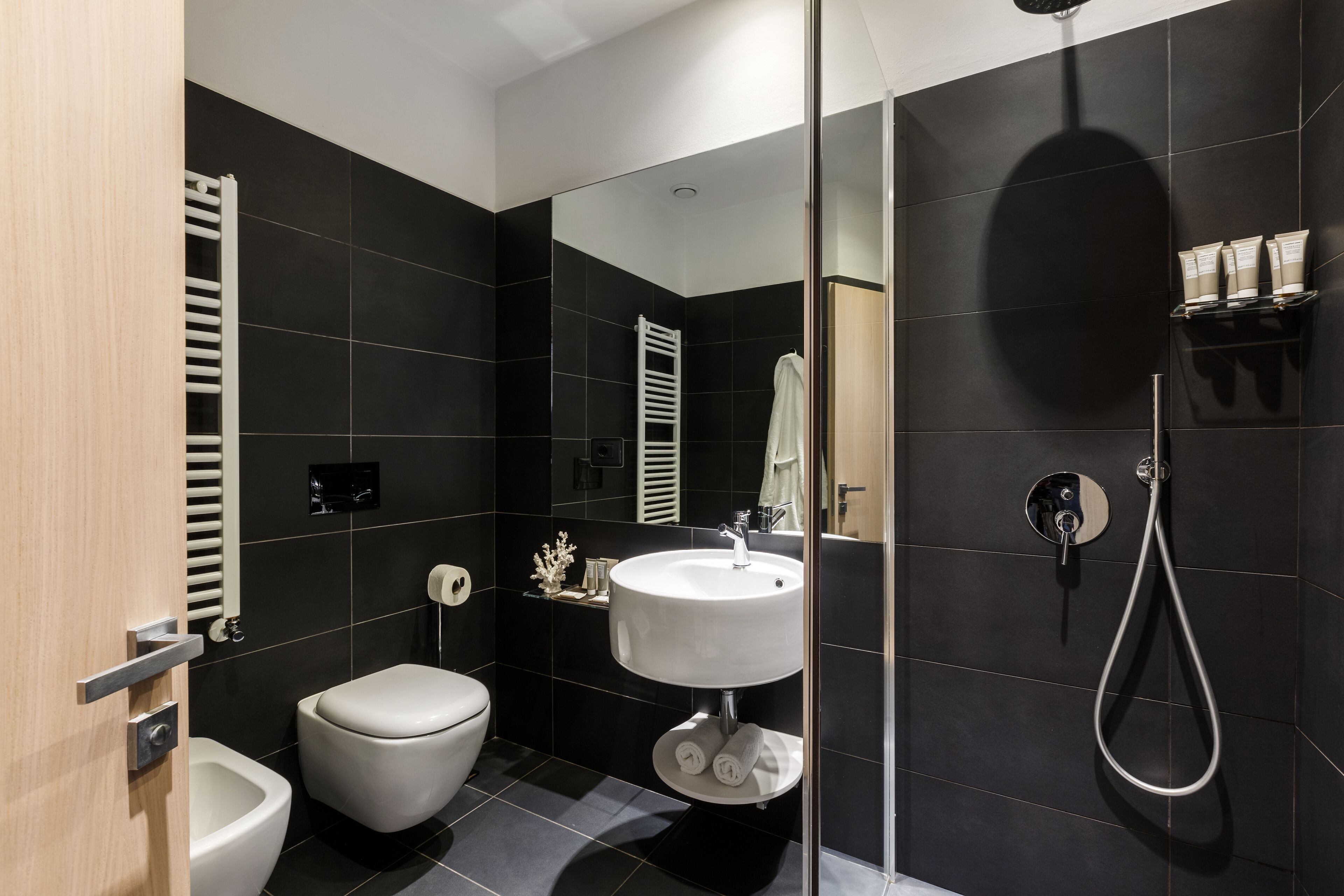 A modern bathroom with a toilet, bidet, and a sink with a handheld showerhead.