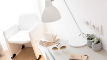 A modern, minimalist workspace with a white chair, desk, and lamp.