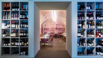 Una bodega con estantes llenos de botellas de vino y un área de comedor con mesas y sillas.
