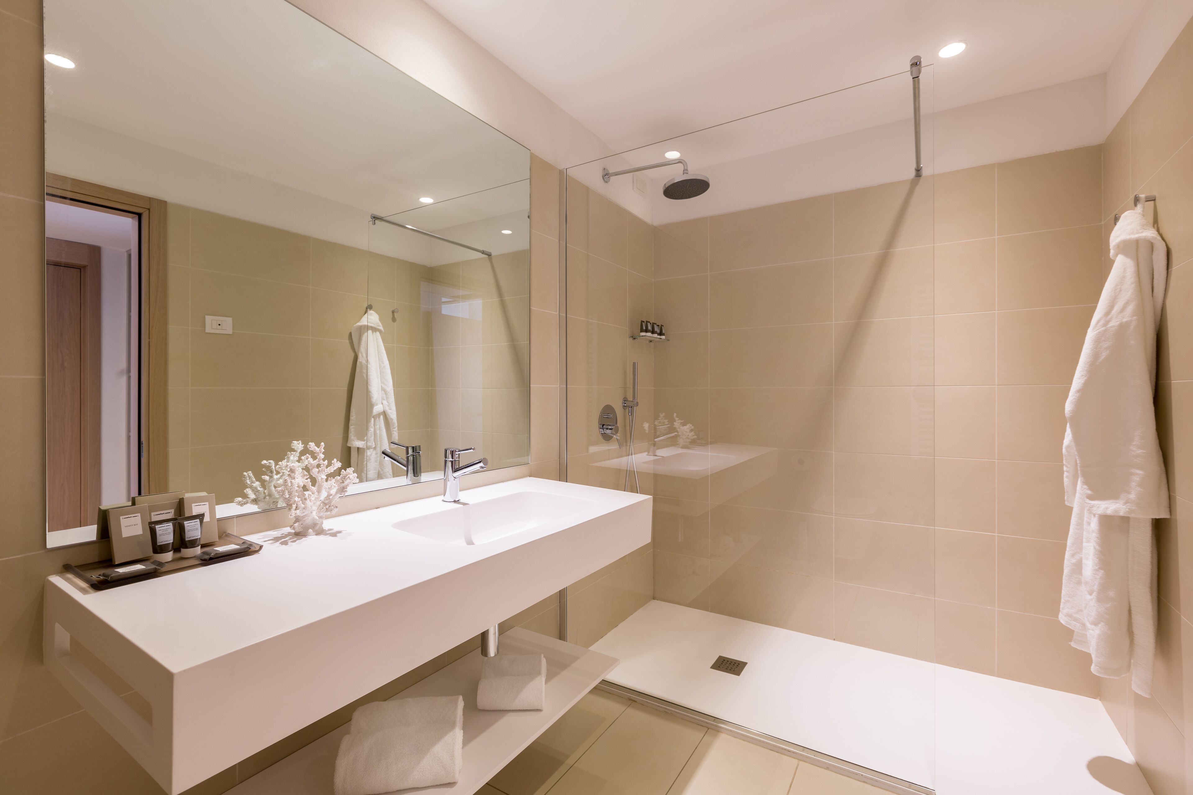 Un baño moderno con un espejo grande, un lavabo blanco, una ducha y un perchero para toallas.