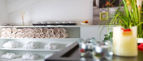 A hotel room with neatly rolled towels on shelves, a minibar, and a wall-mounted TV displaying a comfort zone advertisement.