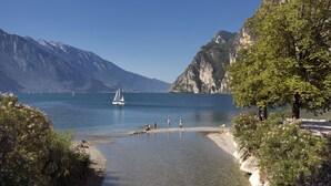 A lake with a sailboat, surrounded by mountains and trees. - Hotel Lago di Garda (Nago-Torbole)