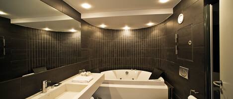 A modern bathroom with a large bathtub, a separate sink, and a toilet.