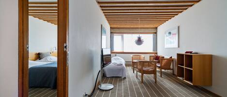 Habitación de hotel con cama, escritorio, silla, radiador y ventana.