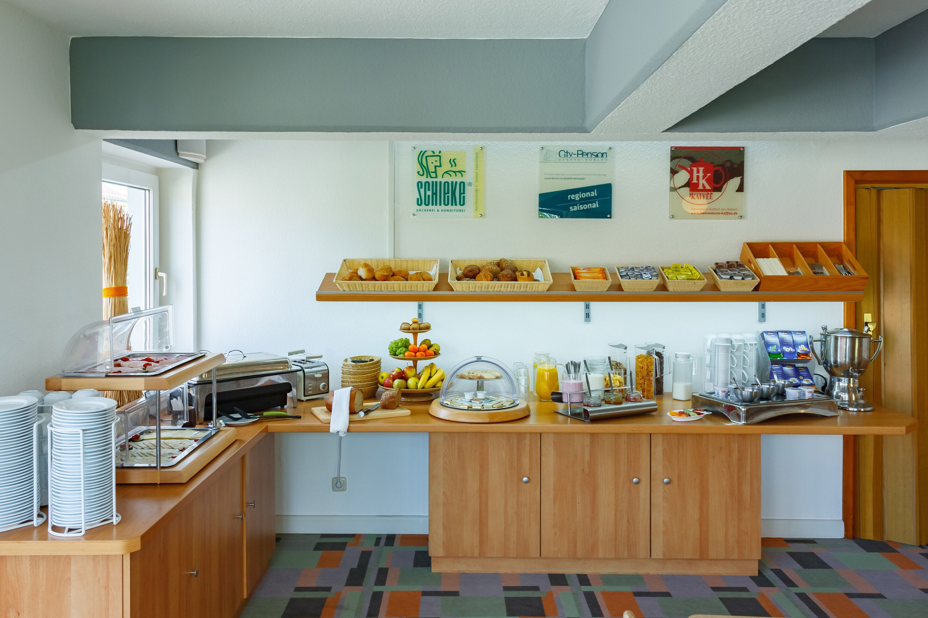 Montaje de bufé con diversas opciones de comida, una estación de café y una exhibición de frutas.