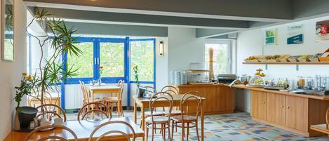 A modern kitchen with wooden furniture, a blue door, and a patterned floor.