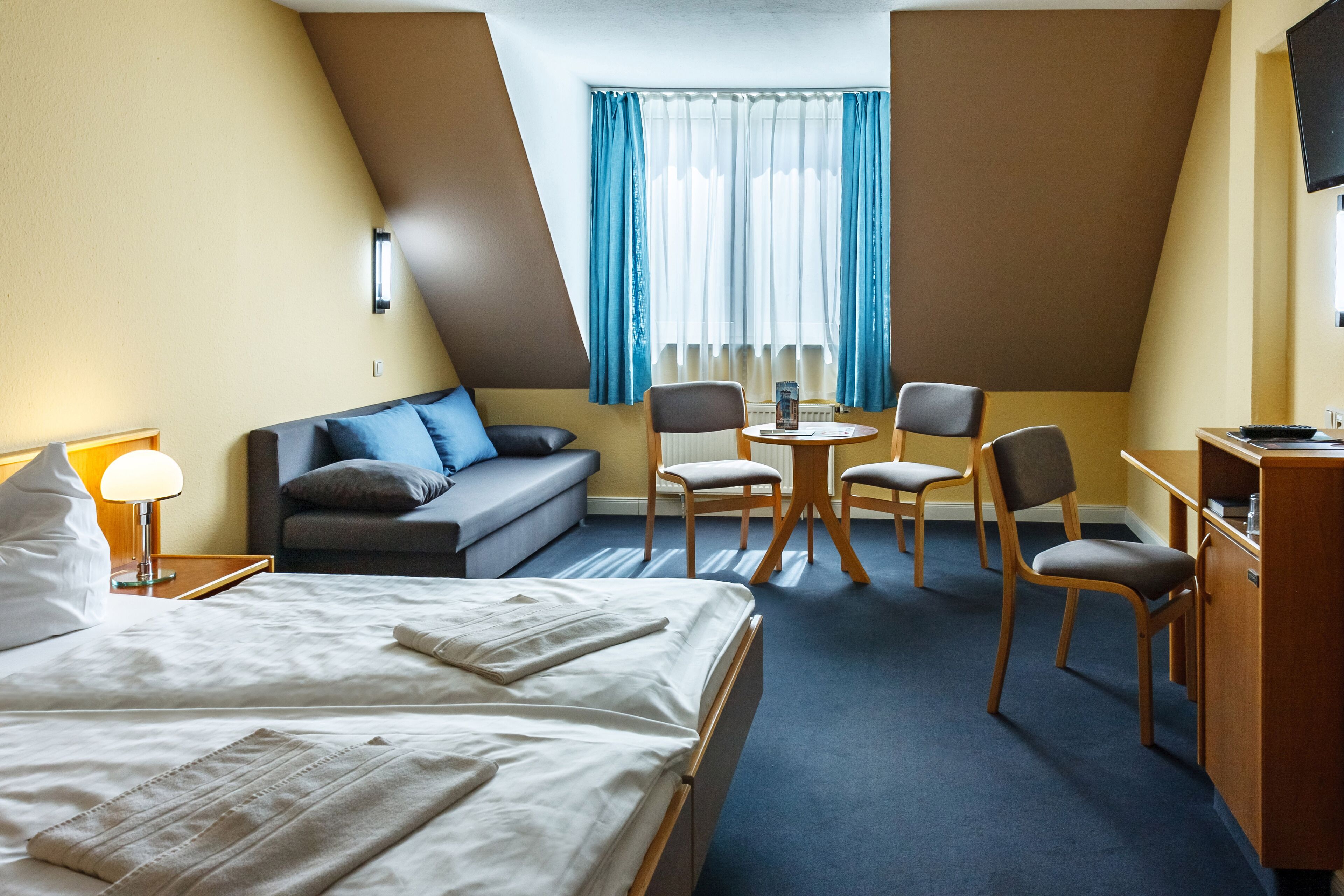 Een hotelkamer met een bed, een bank, een bureau en een stoel.