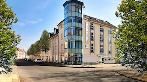 Un immeuble d’angle avec une tour en verre bleue, une entrée bien visible et une enseigne indiquant « City Pension ».