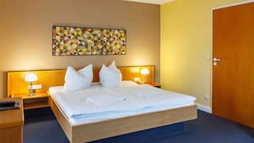 Een hotelkamer met een bed, twee nachtkastjes, een kunstwerk aan de muur, een deur en een lichtschakelaar.