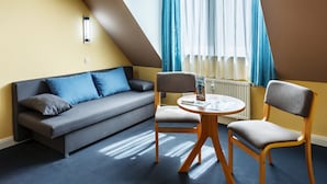 Une pièce moderne comprenant un canapé, deux fauteuils, une petite table et une fenêtre avec des rideaux.