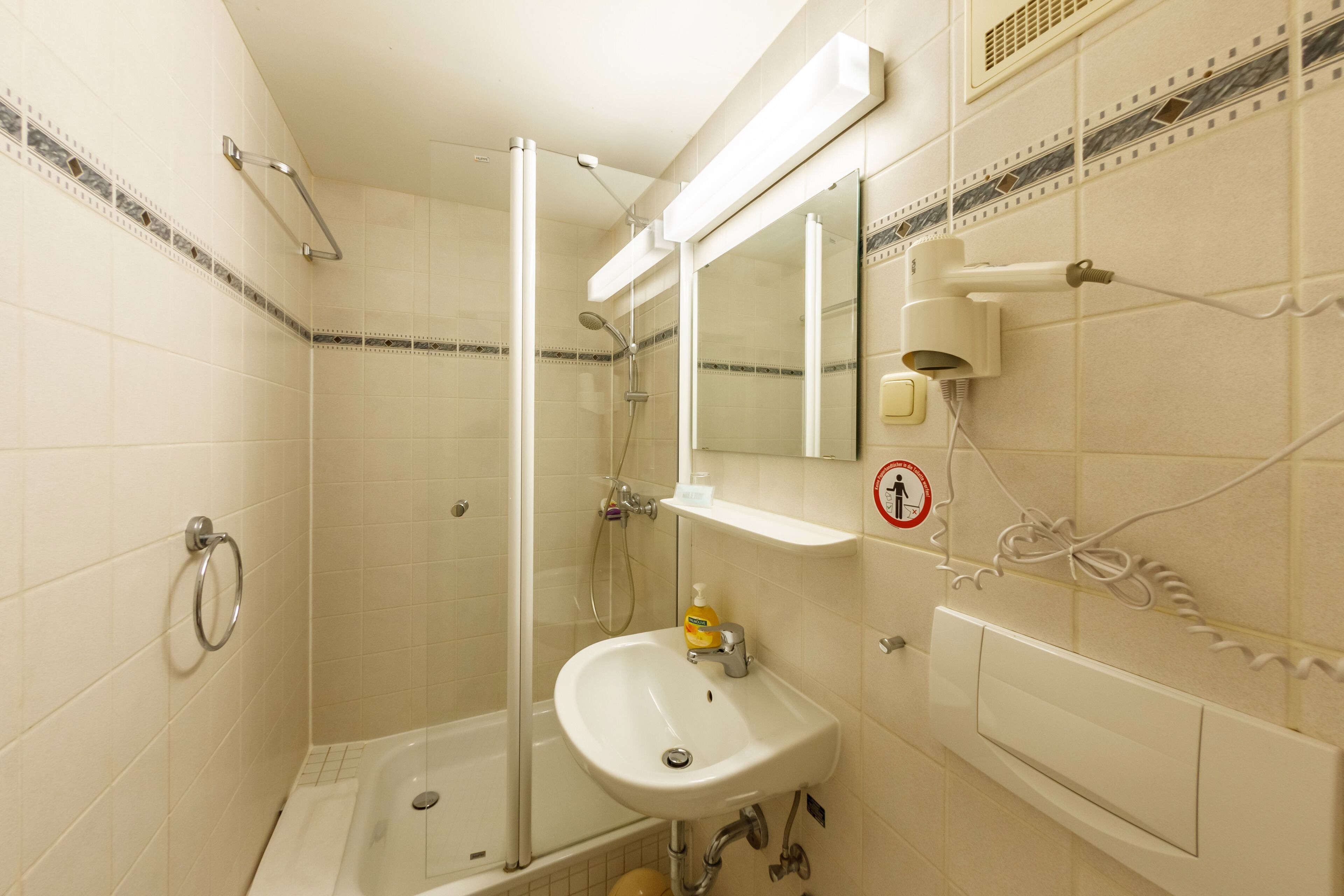 Een badkamer met een douche met glazen wand, een wastafel en een spiegel.
