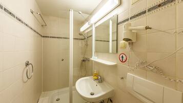 Een badkamer met een douche met glazen wand, een wastafel en een spiegel.