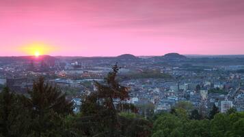 A cityscape at sunset with a view of buildings and a distant hill.