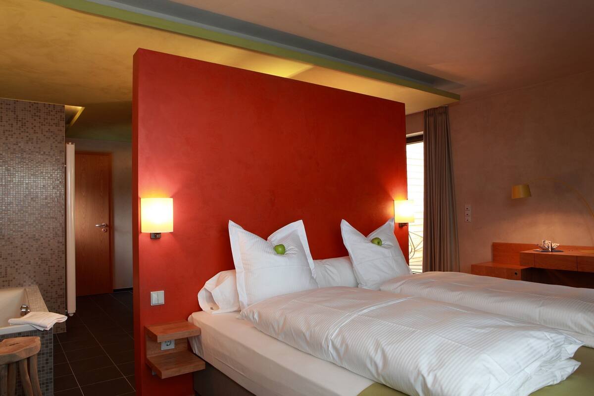 A hotel room with a large bed, two bedside tables, a nightstand, a lamp, and a view of the hallway.