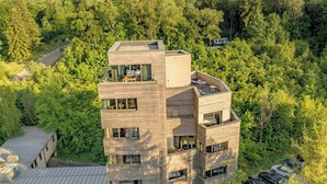 A multi-story building with a flat roof, surrounded by dense forest. - The Seven Hotel (Esch-sur-Alzette)