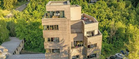 A multi-story building with a flat roof, surrounded by dense forest.