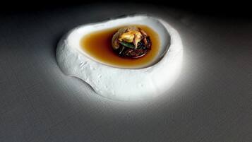A dish with a spherical shape and a sauce in the center, placed on a textured surface.