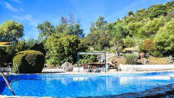 Relax by the serene pool surrounded by lush greenery and natural rock formations.