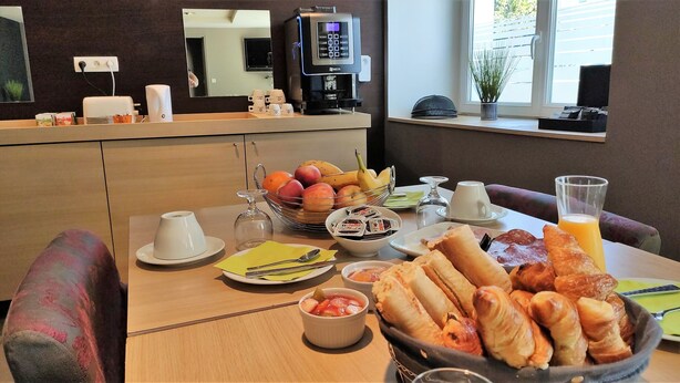 Ein Frühstücksbuffet mit Früchten, Gebäck, Kaffee und Saft.