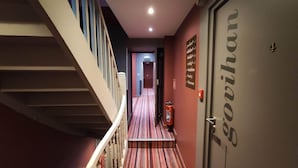 Ein Hotelkorridor mit Treppe, Feuerlöscher und einer Tür mit der Aufschrift 'Govihan'.