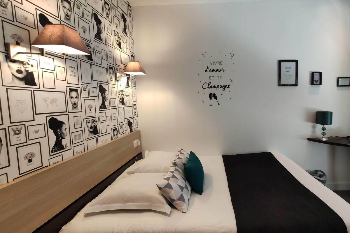 A modern hotel room with a bed, a desk, and a wall decorated with framed pictures.