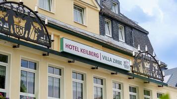 Un hotel llamado HOTEL KEILBERG VILLA ZIRBE con un letrero, varias ventanas y una torre del reloj.