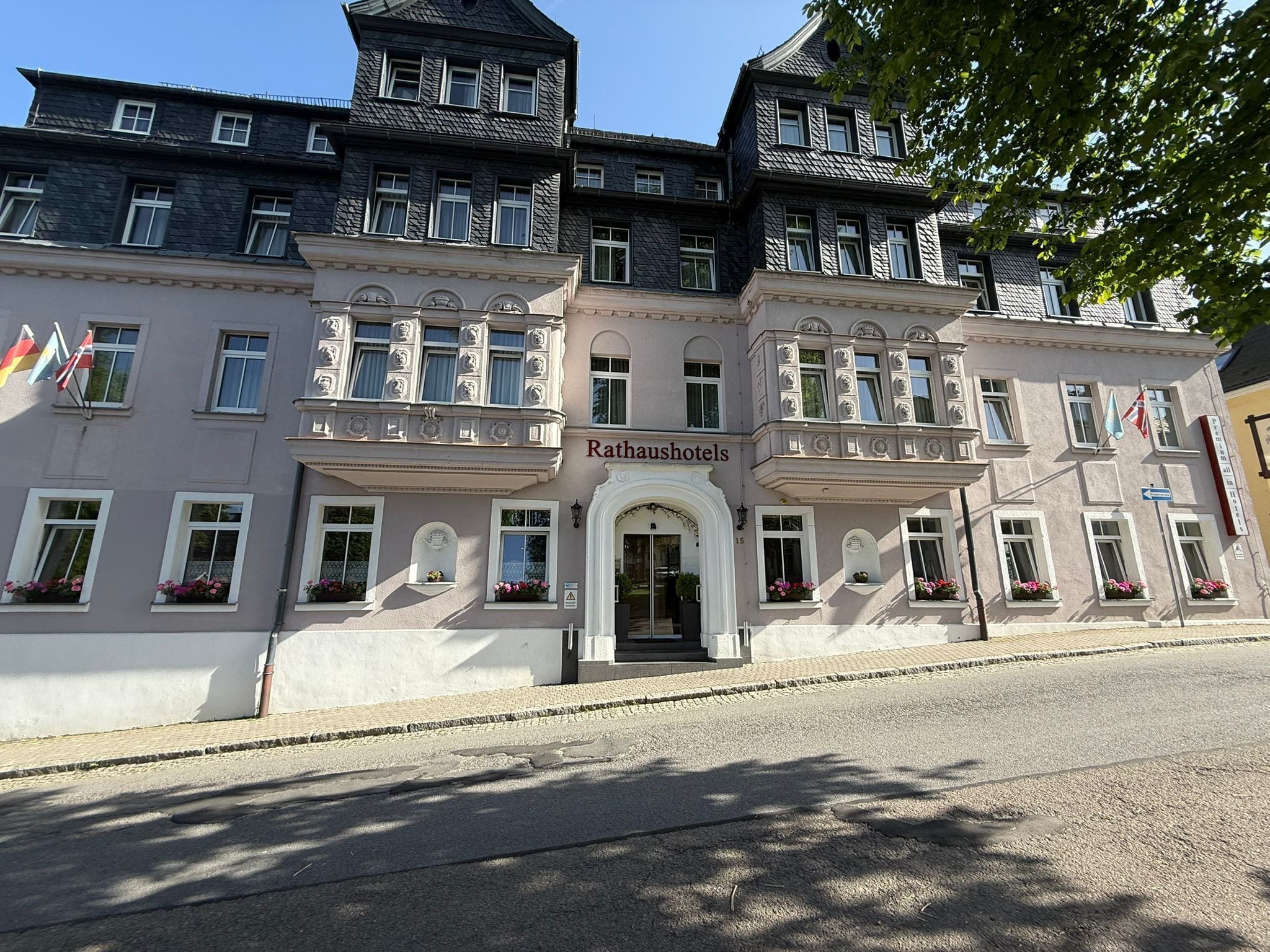 A historic building with a central entrance, multiple windows, and flags.
