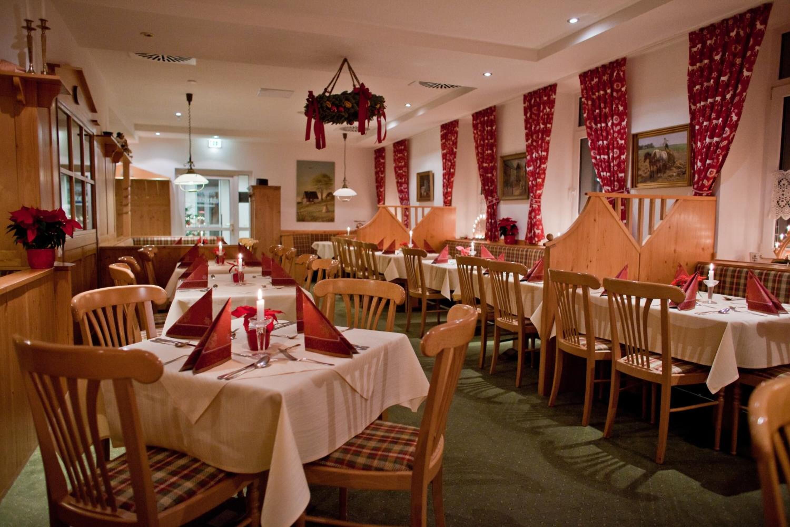 A dining area with multiple tables set for guests, wooden chairs, and a cozy atmosphere.