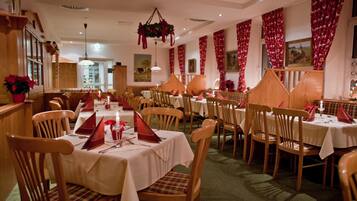 A dining area with multiple tables set for guests, wooden chairs, and a cozy atmosphere.