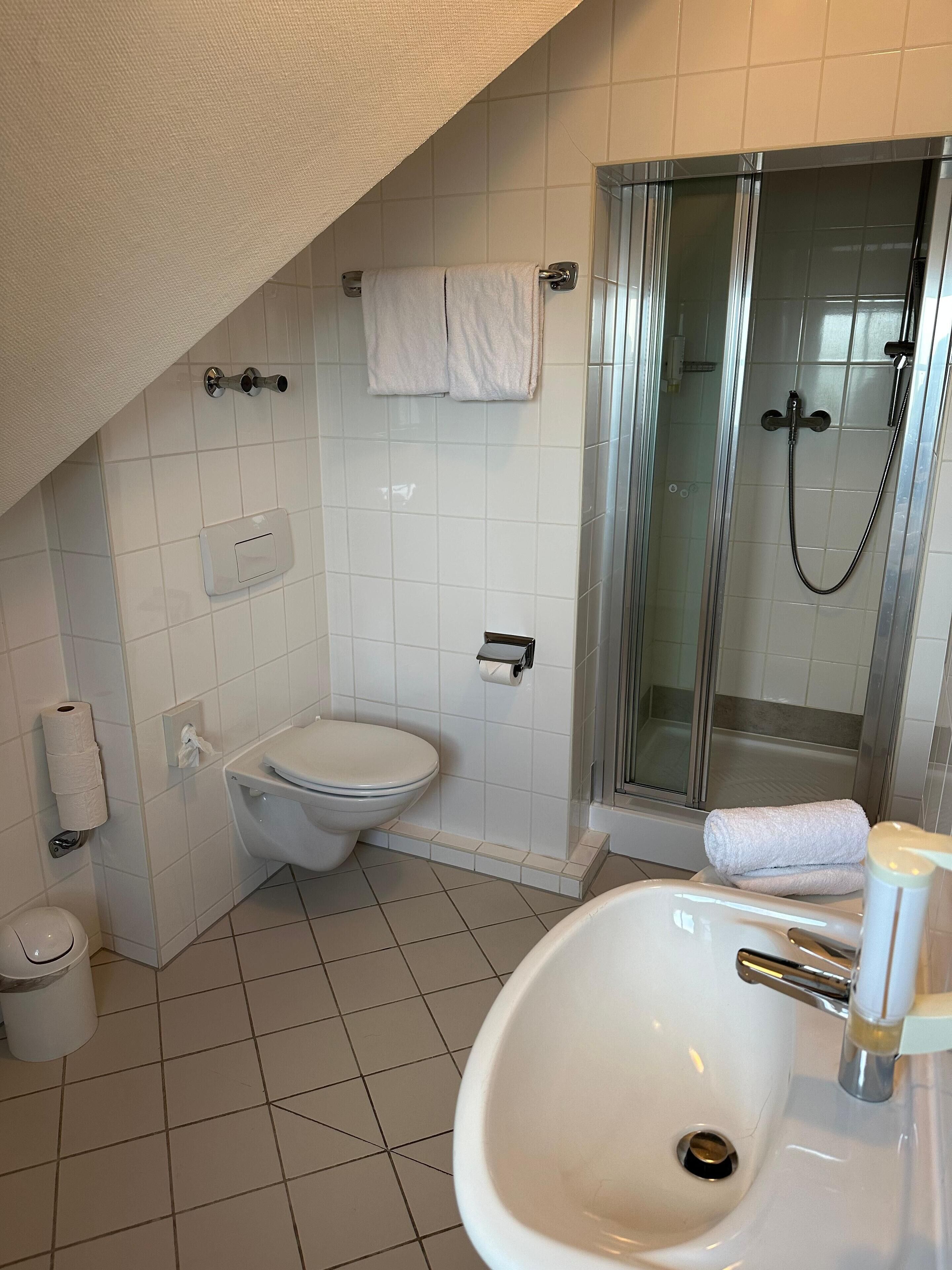 Une salle de bain moderne équipée de toilettes, d’un lavabo et d’une douche à parois de verre.