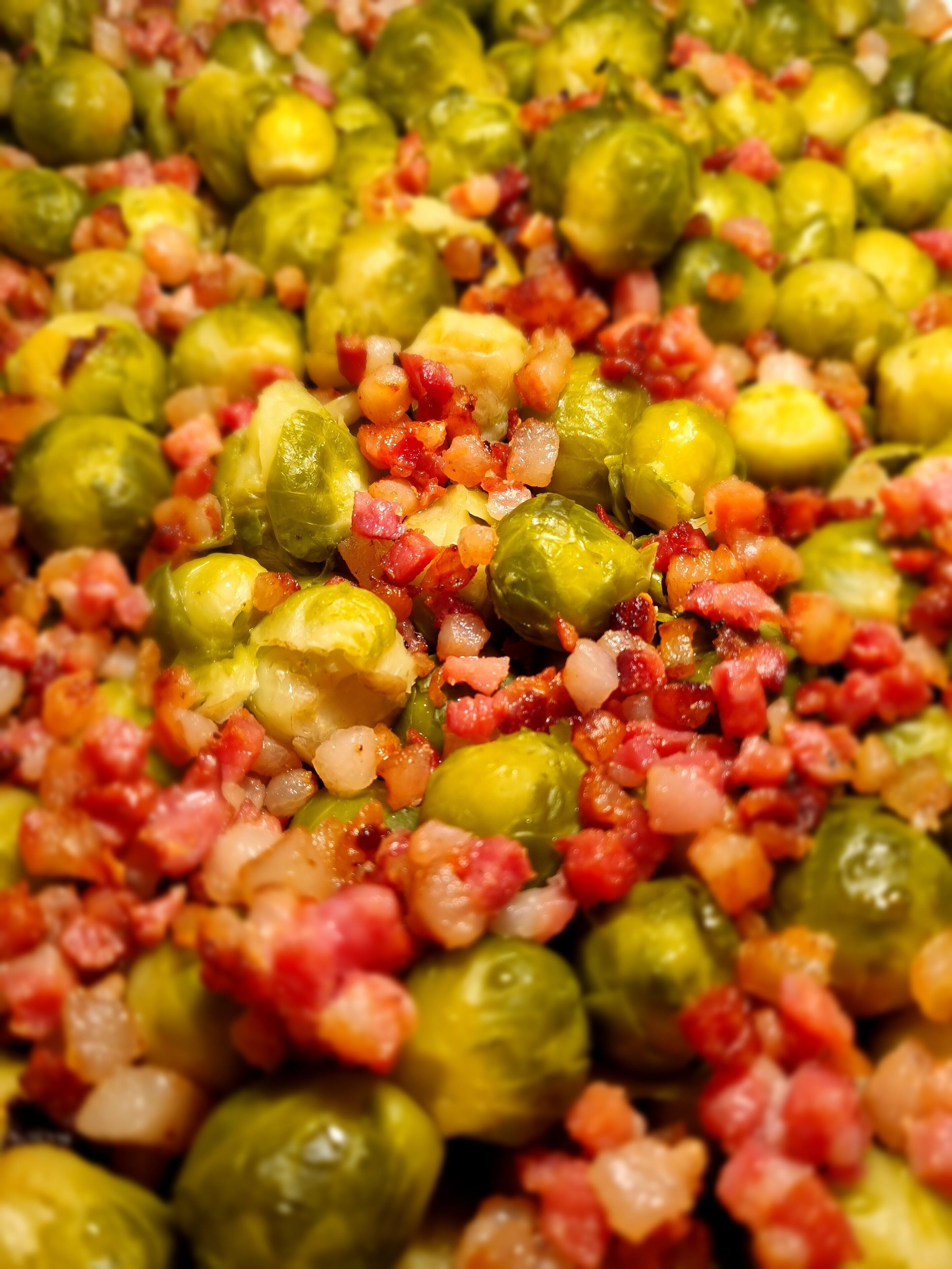 Ein Detailfoto von Rosenkohl, gewürfeltem Speck und Zwiebeln.