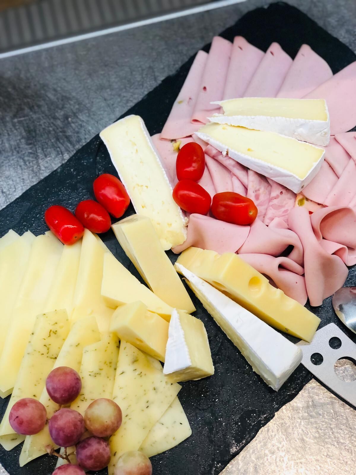 A charcuterie board with various cheeses, cured meats, and grapes.