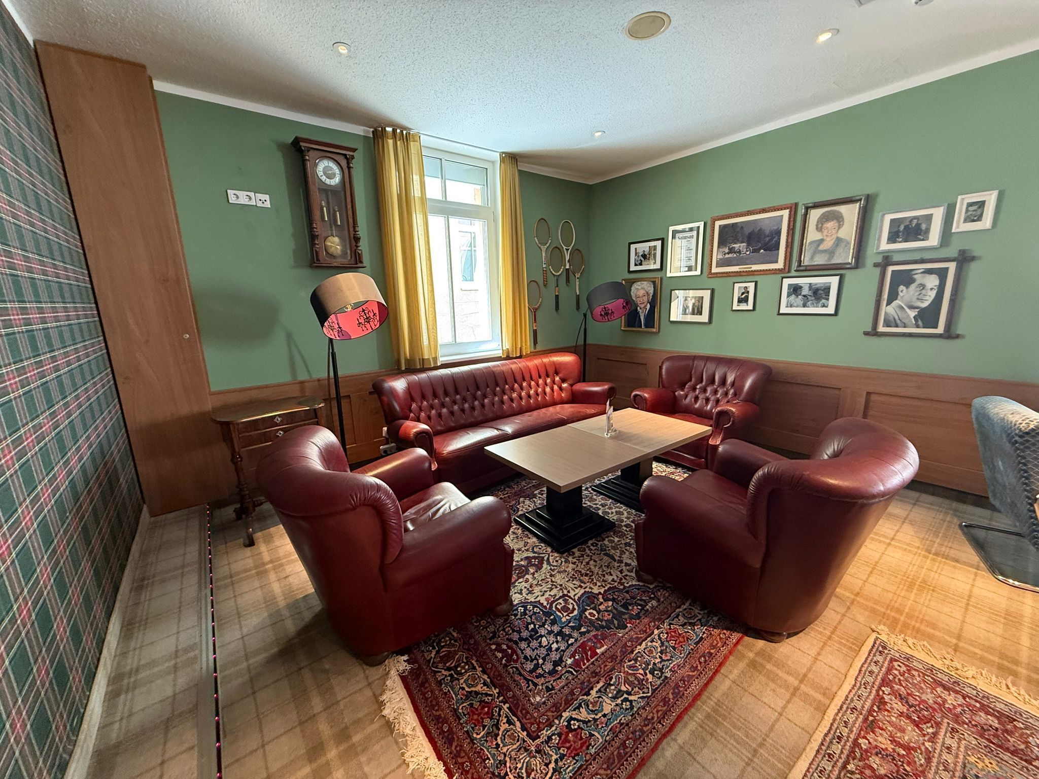 Un salon avec un ensemble de canapés en cuir rouge, une table basse en bois et un tapis à motifs.
