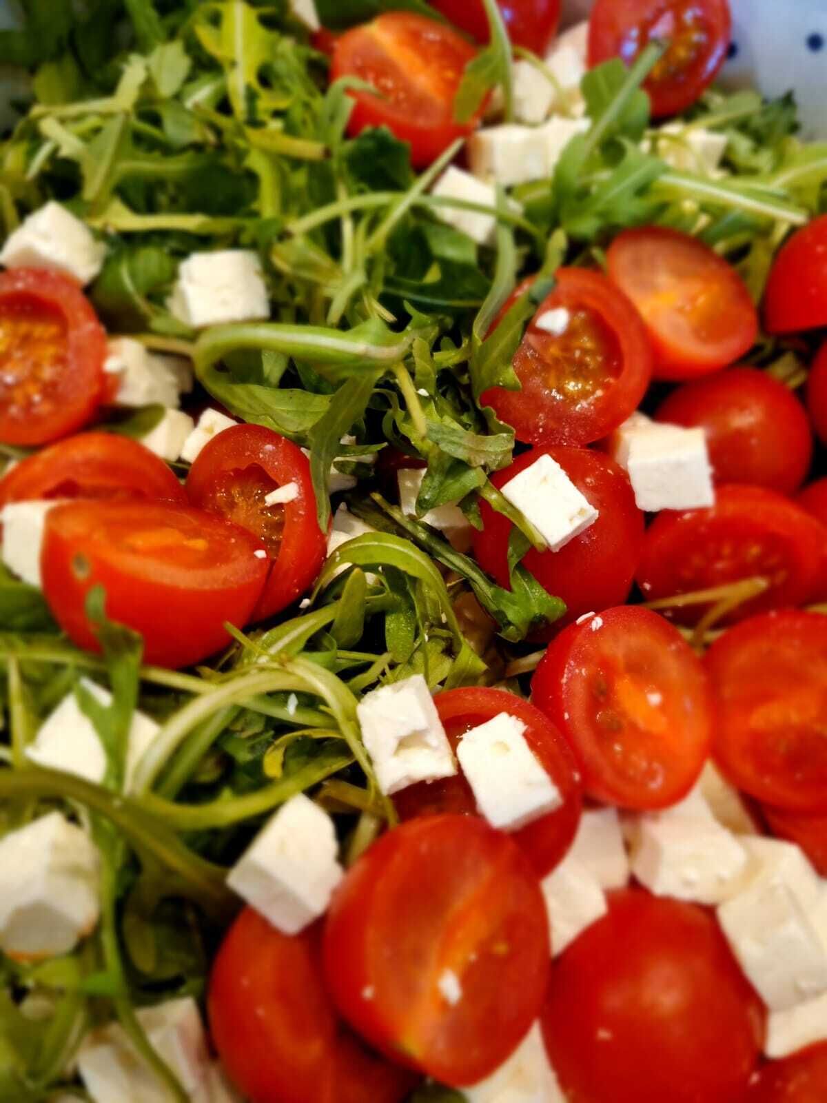 A salad with arugula, cherry tomatoes, and feta cheese.