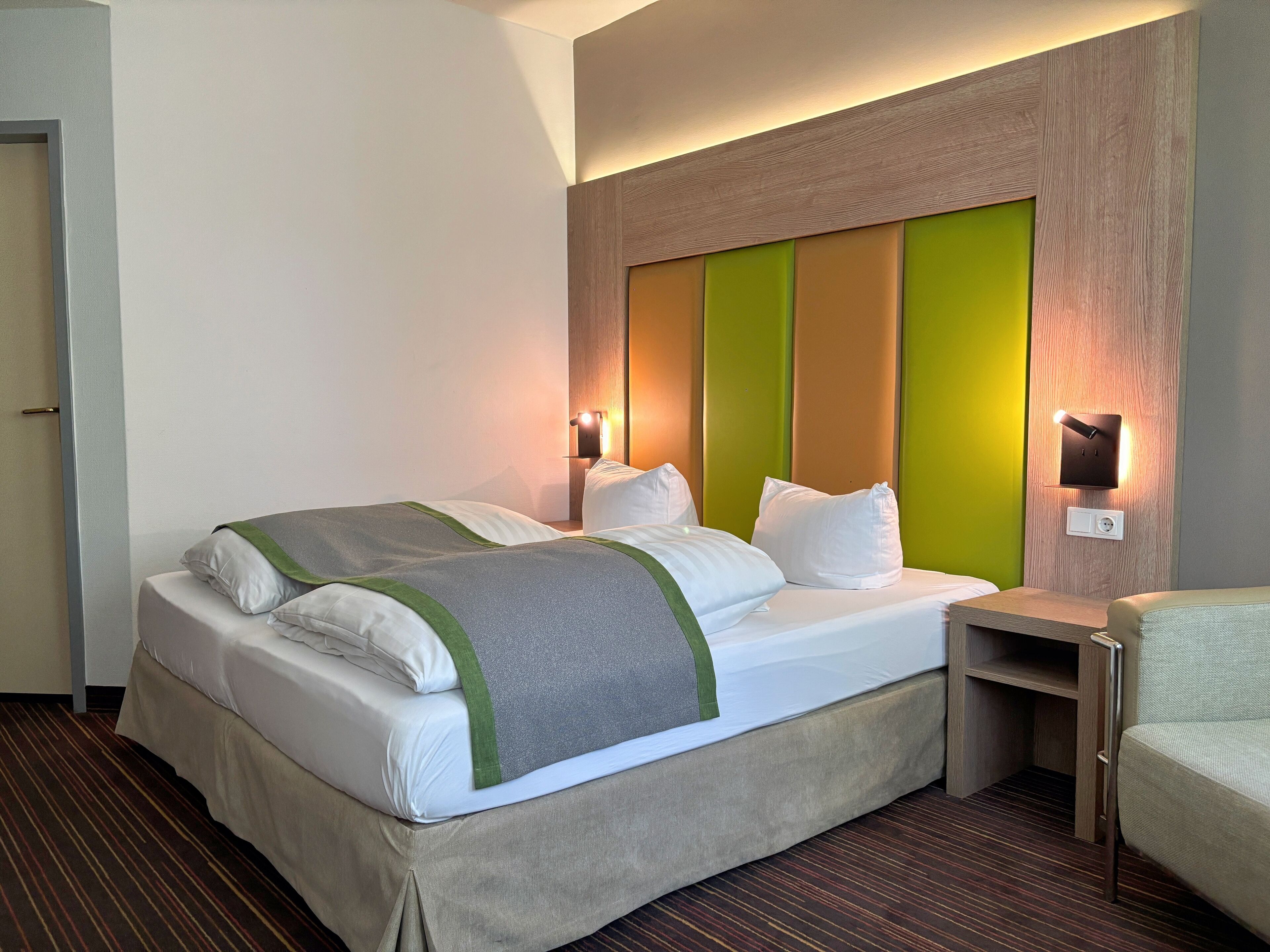 Quarto de hotel com cama, mesas de cabeceira e um criado-mudo.