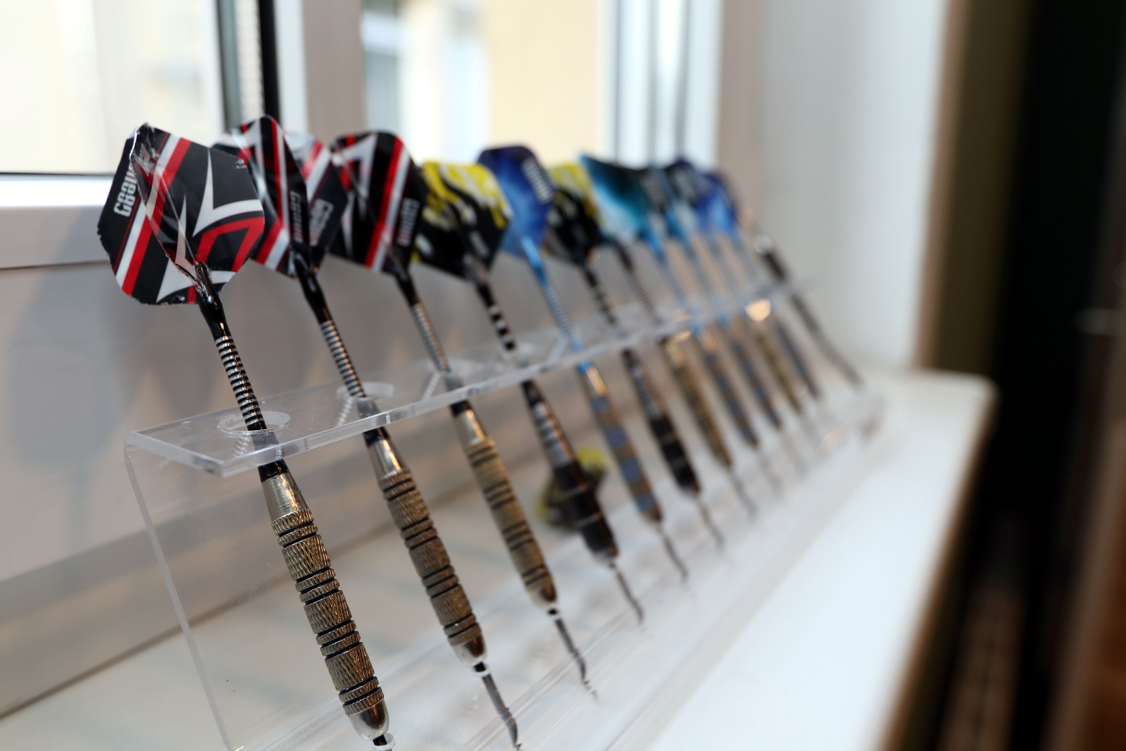 A display of darts with various designs on a transparent stand.