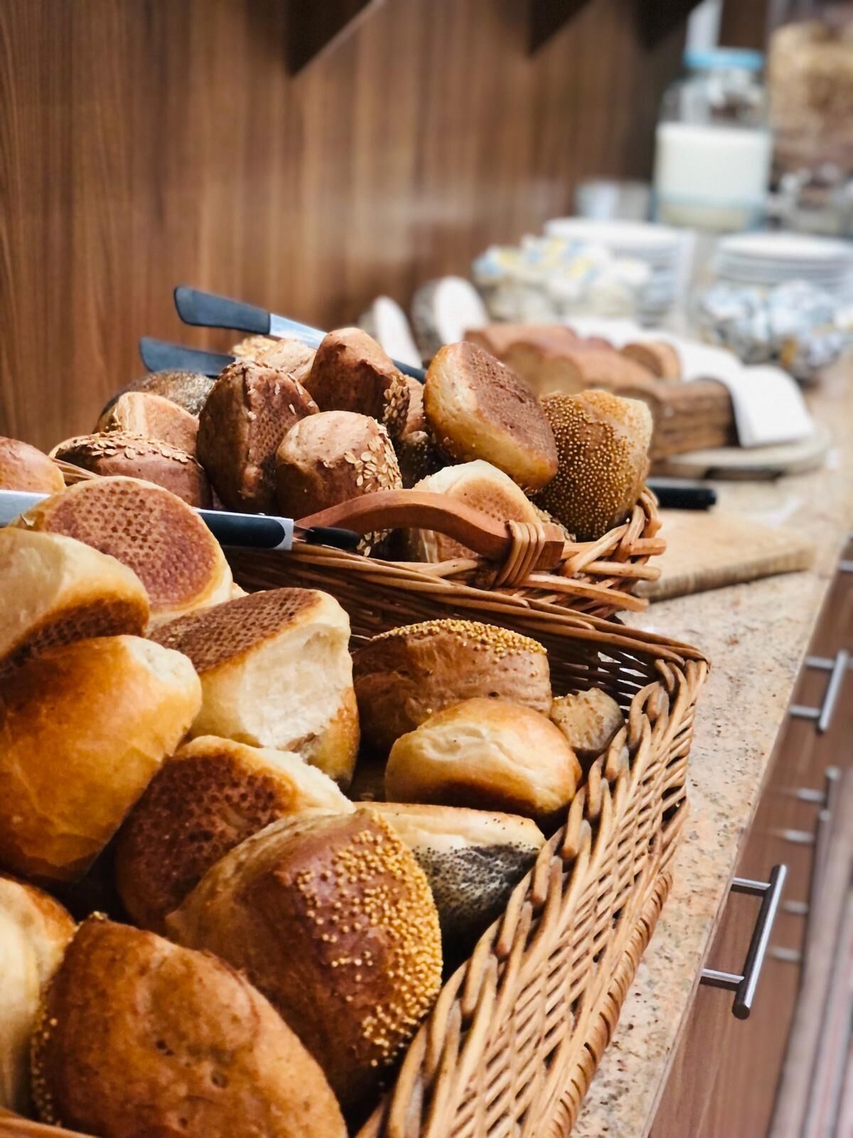 A variety of breads and pastries displayed in a wicker basket on a countertop.