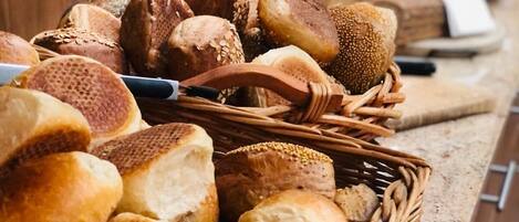 A variety of breads and pastries displayed in a wicker basket on a countertop.