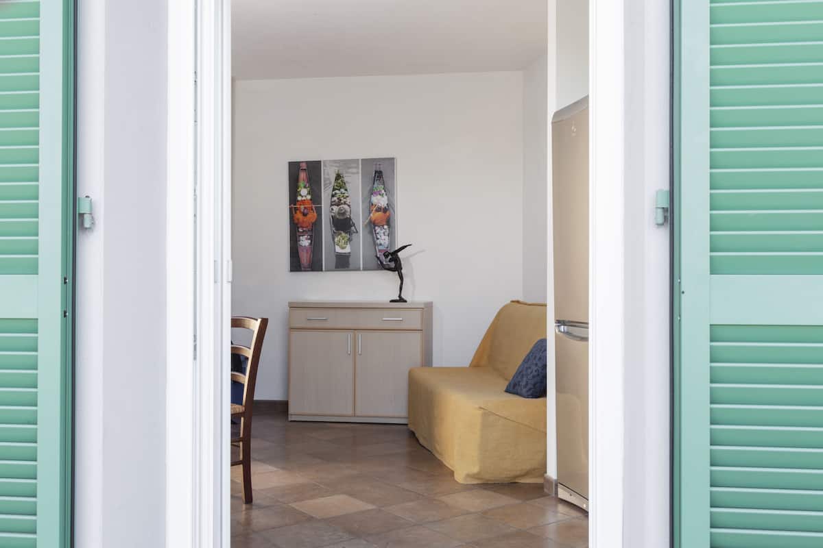 Een kamer met een bed, een stoel, een kast en een schilderij aan de muur.