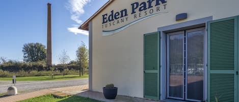 Eden Park Tuscany Resort with a clear sky, a chimney in the background, and a potted plant in front.