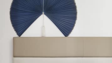 A neatly arranged bedroom with a bed, a bedside table, and a wall-mounted fan.