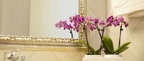 Un baño con un lavamanos, un espejo y dos orquídeas en macetas.