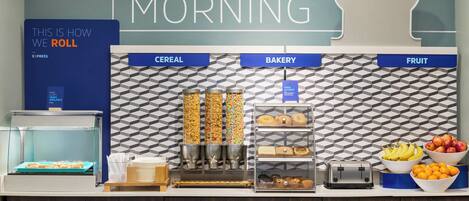 A breakfast buffet area with labeled sections for cereal, bakery, and fruit.