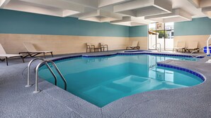 A swimming pool with a blue tiled edge, surrounded by lounge chairs and a modern ceiling design. - Holiday Inn Express Hotel & Suites Waycross by IHG (Waycross)