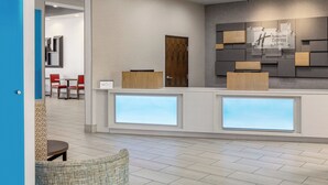 A hotel reception area with a modern design, including a reception desk, seating area, and a wall-mounted sign for the Holiday Inn Express & Suites. - Holiday Inn Express Hotel & Suites Waycross by IHG (Waycross)